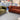 Green velvet Chesterfield armchair and rust-colored button-tufted 3 seater sofa set in showroom setting