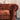 Close-up of deep button-tufted armrest on a rust fabric Chesterfield sofa in a warehouse showroom setting
