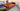 Rust-colored Chesterfield 3-seater fabric sofa with deep tufting and rolled arms in a showroom display setting