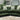 Green fabric corner sofa with striped and white cushions in a modern living room setting on a beige rug