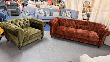 Green velvet Chesterfield armchair and rust-colored button-tufted 3 seater sofa set in showroom setting