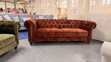 Rust velvet Chesterfield 3 seater sofa with button tufting and rolled arms in industrial showroom setting
