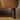 Close-up of tapered dark wooden leg supporting a tan leather armchair on hardwood flooring